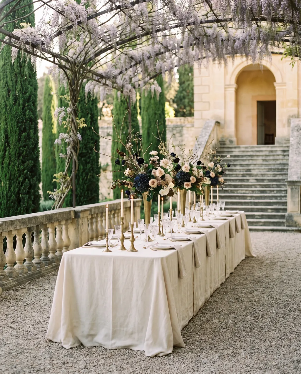 A dressed table for thirty running the length of a walled garden at dusk